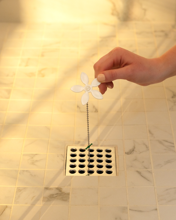 white-daisy|DrainWig hair catcher being installed in shower drain