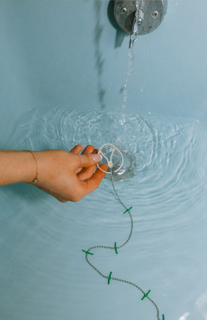 Hand holding DrainWig in bathtub 