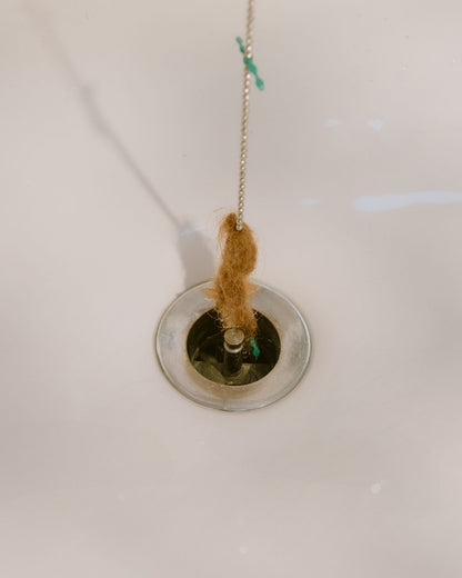 DrainWig hair catcher pulling hair out of the bathtub drain